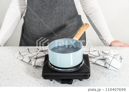 Melting chocolate chips and other ingredients in a glass mixing bowl over boiling water to prepare pumpkin spice fudge. 110407699
