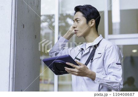 作業服を着てタブレットを見ながらビルの点検作業をする若い男性　撮影協力:有明教育芸術短期大学 110408687