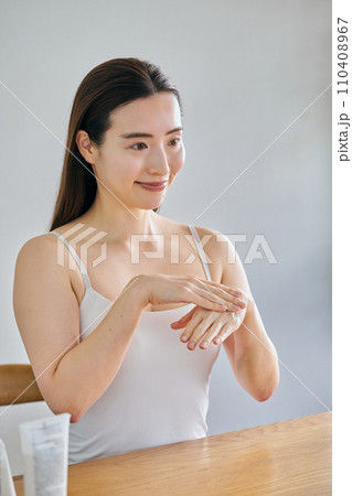 ハンドクリームを手につけてマッサージする30代女性 110408967