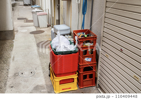 店の裏に置かれたビールケースと積み重なった買い物かご 店の裏に置かれたビールケースと積み重なった買い物かご 110409448