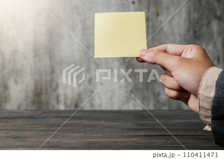 A business hand holding a piece of empty notepaper 110411471