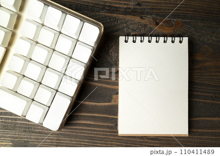 Closeup view of a computer keyboard with an empty notebook Closeup view of a computer keyboard with an empty notebook 110411489