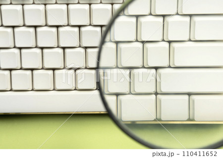 A closeup view of a magnifying glass focuses on a computer keyboard button A closeup view of a magnifying glass focuses on a computer keyboard button 110411652