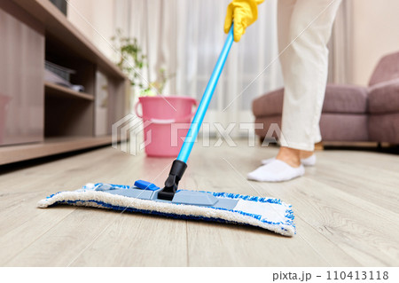 young woman cleaning and mopping floor at living room, daily housekeeping , Cropped 110413118