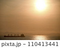 夕陽をバックに進む貨物船 110413441