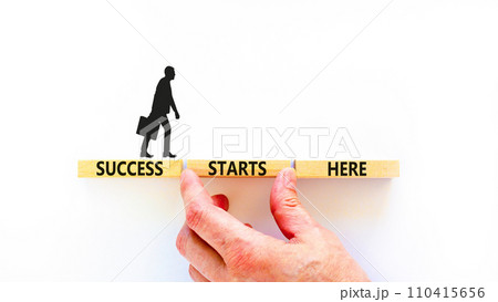 Success starts here symbol. Concept word Success starts here on beautiful wooden block. Businessman hand. Beautiful white background. Business motivational success starts here concept. Copy space. Success starts here symbol. Concept word Success starts here on beautiful wooden block. Businessman hand. Beautiful white background. Business motivational success starts here concept. Copy space. 110415656