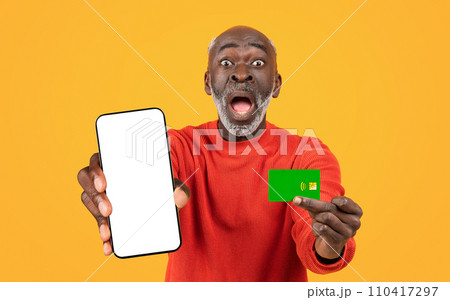 Shocked funny old black man with open mouth show credit card and phone with blank screen Shocked funny old black man with open mouth show credit card and phone with blank screen 110417297