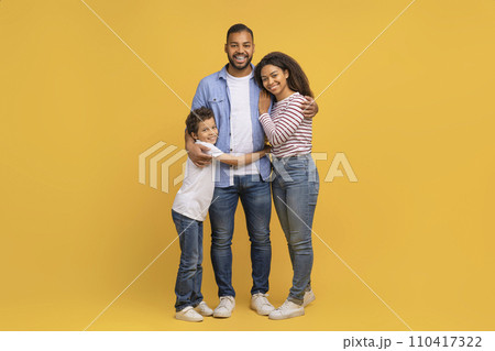 Family Portrait. Happy Black Parents And Preteen Son Embracing Over Yellow Background 110417322