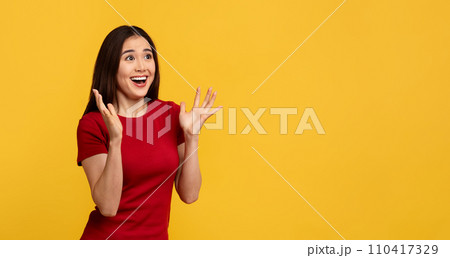 Amazed young korean woman looking at copy space and gesturing Amazed young korean woman looking at copy space and gesturing 110417329