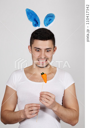 Handsome young man in rabbit ears on a white background. Easter concept Handsome young man in rabbit ears on a white background. Easter concept 110417342