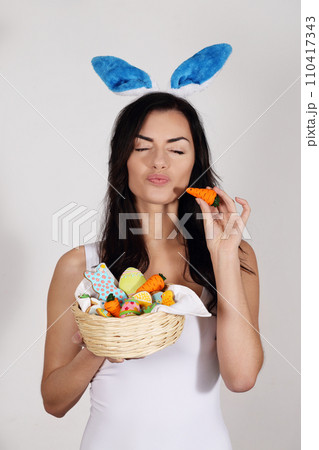 Beautiful woman with bunny ears with a basket of Easter desserts 110417343