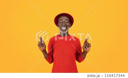Content senior black man with closed eyes and a serene smile, wearing a red sweater and hat Content senior black man with closed eyes and a serene smile, wearing a red sweater and hat 110417344