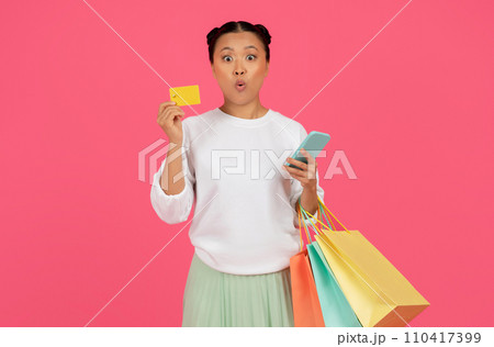 Shocked Asian Woman Holding Smartphone, Credit Card And Shopping Bags Shocked Asian Woman Holding Smartphone, Credit Card And Shopping Bags 110417399