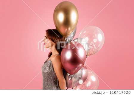 A serene woman in a sparkling silver dress gazes into the distance, her profile 110417520