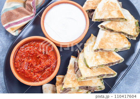 Fajita quesadilla with pieces of beef steak, green bell pepper, onion and cheese, top view 110417604