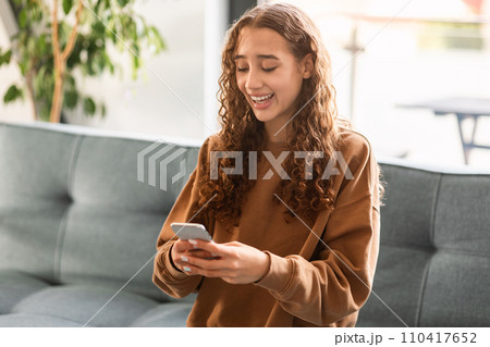 teen girl websurfing on cellphone engaged in online leisure indoor 110417652