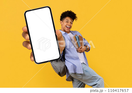 Happy black guy student showing smartphone screen on yellow backdrop Happy black guy student showing smartphone screen on yellow backdrop 110417657