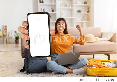 Excited young asian woman tourist showing phone with blank screen 110417699