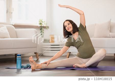 Young pregnant lady practicing gentle side bends exercising at home 110418015