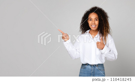 Cheerful Black Lady Gesturing Thumbs Up Pointing Finger Aside, Studio Cheerful Black Lady Gesturing Thumbs Up Pointing Finger Aside, Studio 110418245
