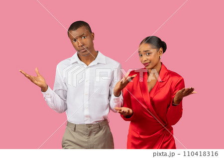Confused black couple shrugging, wearing elegant attire, pink background Confused black couple shrugging, wearing elegant attire, pink background 110418316