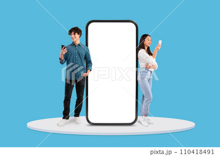 Young man and woman with phones by large blank display 110418491