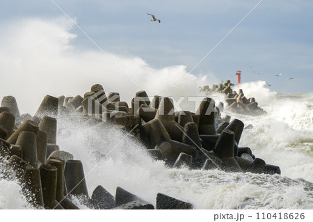 Storm at sea, high waves crashing against the concrete breakwaters of the port, high white splashes 110418626