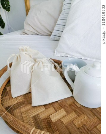 Cotton bags on a bamboo tray in a hotel room with a white bed Cotton bags on a bamboo tray in a hotel room with a white bed 110419332