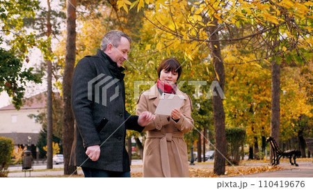 Man and woman look at work schedule on tablet during meeting in city park Man and woman look at work schedule on tablet during meeting in city park 110419676