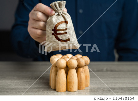 A man is holding a euro money bag over a group of people figurines. Generation of funds from cooperation. Organization of the community budget. Payment for labor and services. Political lobbying. 110420154