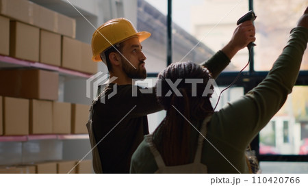 African american warehouse manager and assistant perform inventory inspection, keeping quality standards high. Focused experts in storeroom prepare to ship parcels, crosschecking delivery info 110420766