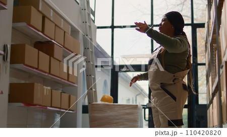 Manager in warehouse using AR holographic technology to visualize how to best stash parcels on shelves to make room for more. Supervisor in distribution center uses augmented reality Manager in warehouse using AR holographic technology to visualize how to best stash parcels on shelves to make room for more. Supervisor in distribution center uses augmented reality 110420820