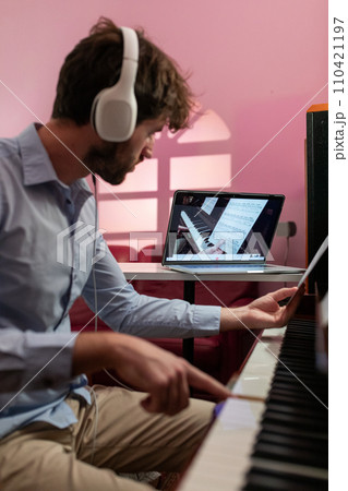 Man Learning Piano Music Lesson With Remote Video Assistant Man Learning Piano Music Lesson With Remote Video Assistant 110421197