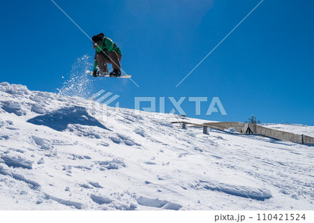Snowboarder jumping against blue sky 110421524