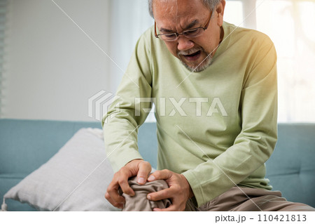 Senior man having painful knee pain after ligament surgery, senior man knee joint pain on sofa at home, Elderly old age pain after falling torn ligament, health problem, Healthcare and medical concept Senior man having painful knee pain after ligament surgery, senior man knee joint pain on sofa at home, Elderly old age pain after falling torn ligament, health problem, Healthcare and medical concept 110421813