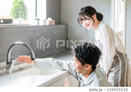 キッチンで水道屋・設備屋の説明を受ける主婦の女性 キッチンで水道屋・設備屋の説明を受ける主婦の女性 110423110