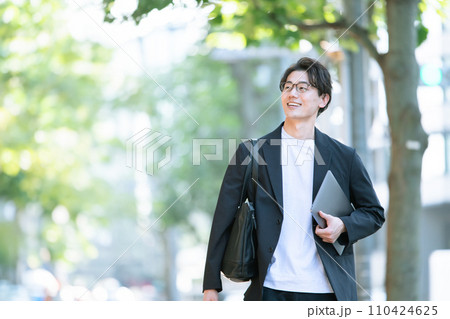 パソコンを持って歩く男性 パソコンを持って歩く男性 110424625