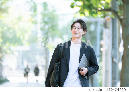 パソコンを持って歩く男性 110424630