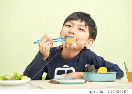 笑顔でお弁当を食べる幼い男の子 110426104
