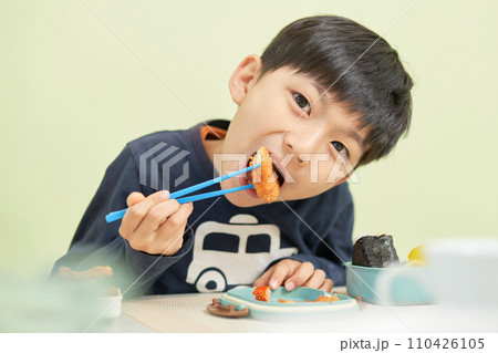 笑顔でお弁当を食べる幼い男の子 110426105