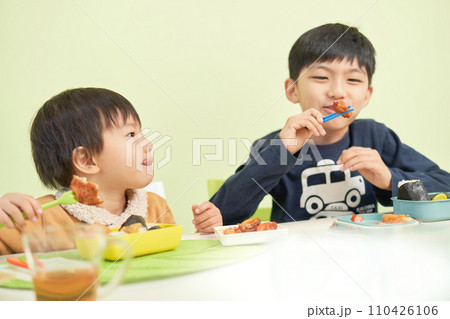 美味しそうにお弁当を食べる2人の男の子 美味しそうにお弁当を食べる2人の男の子 110426106