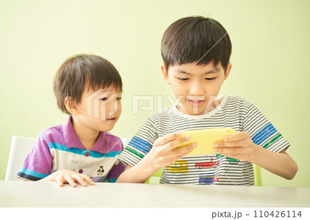 携帯型ゲームを楽しむ2人の男の子 110426114