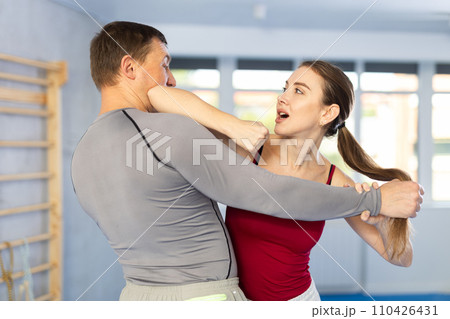 Adult man and young woman training self-defense techniques Adult man and young woman training self-defense techniques 110426431