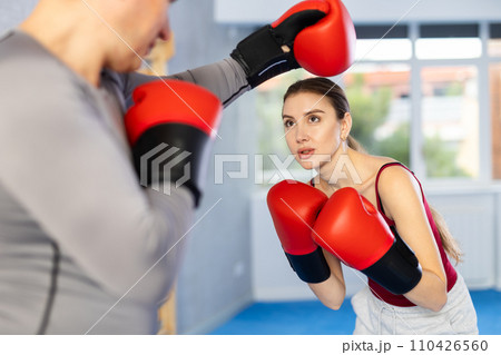 Adult man and young woman train boxing Adult man and young woman train boxing 110426560