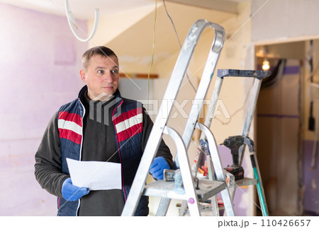 Builder standing at indoors building site, reading document Builder standing at indoors building site, reading document 110426657