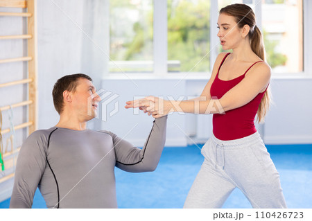 Young woman learns to do painful grip on arm of an attacking man during self defense training Young woman learns to do painful grip on arm of an attacking man during self defense training 110426723