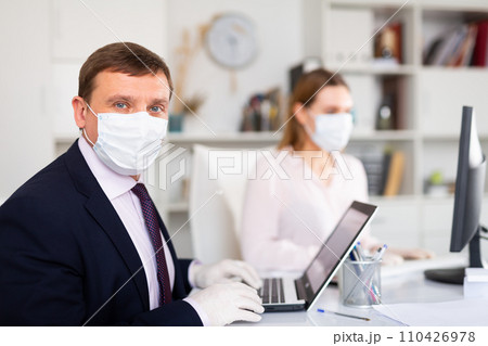 Entrepreneur in medical mask working with female coworker in office 110426978