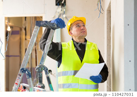 Male contractor looking at room and determining scope of building work 110427031