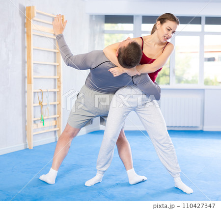 Adult man and young woman training self-defense techniques Adult man and young woman training self-defense techniques 110427347