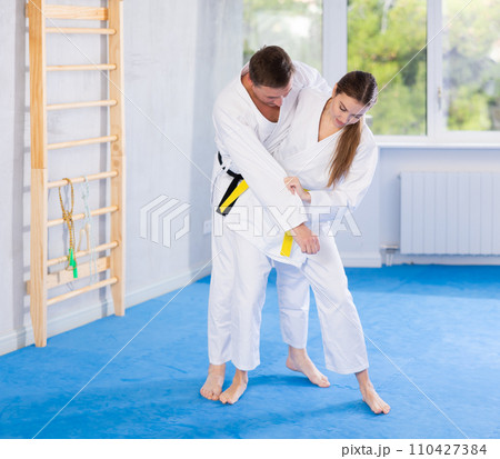 Young girl and middle-aged man wearing kimono training throwing technique Young girl and middle-aged man wearing kimono training throwing technique 110427384